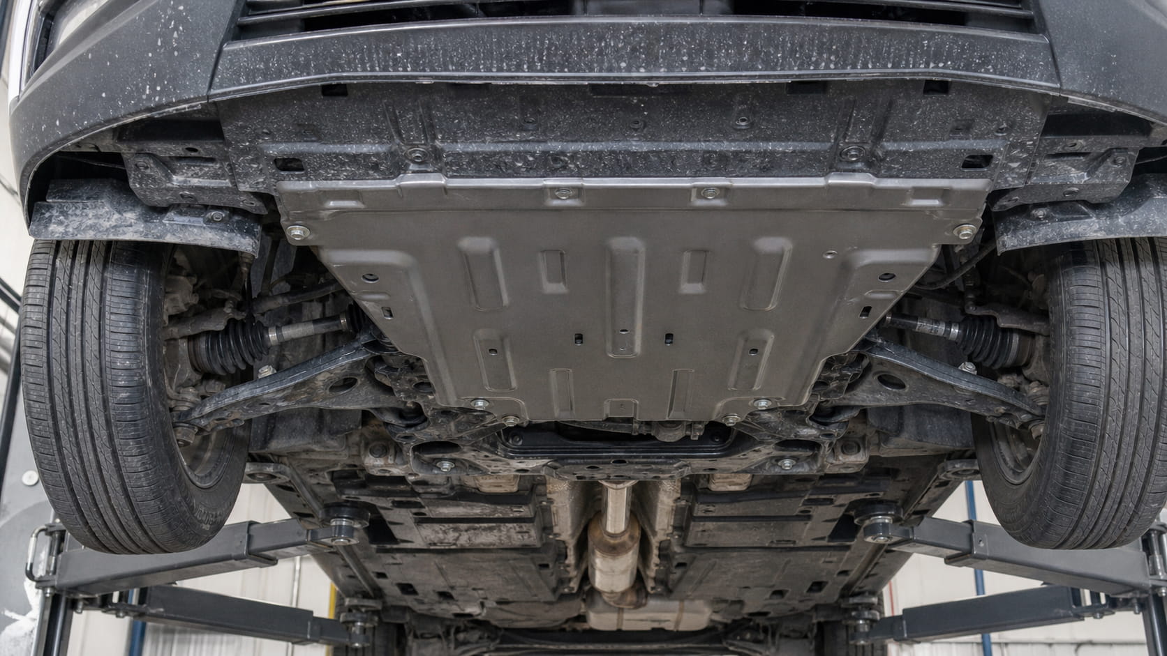 Underbody view of SUV on workshop lift with metal engine skid plate installed